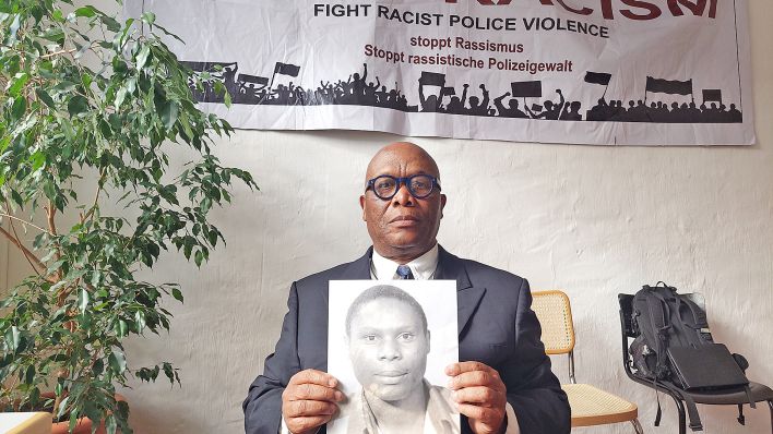 Archivbild: Mutombo Mansamba hält am 11.10.2022 das Foto seines aufgrund von Polizeigewalt gestorbenen Bruders Kupa llunga Medard Mutombo in den Händen. (Quelle: dpa/Salman Ahmed)
