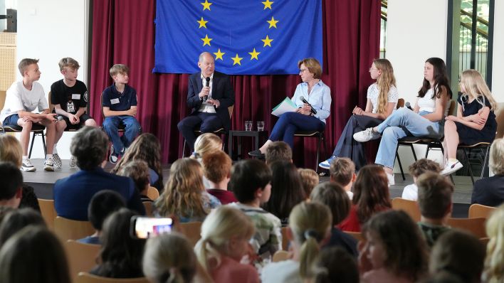 Bundeskanzler Olaf Scholz (SPD) besucht am 22.05.2023 anlässlich des EU-Projekttages die Eigenherd-Schule und beantwortet in der Mensa die Fragen der auf dem Podium sitzenden Schüler der sechsten Klassenstufe. (Quelle: dpa/Soeren Stache)