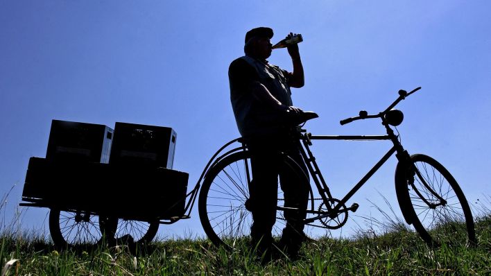 Symbolbild:Nur als Schattenriss ist ein Radfahrer neben seinem Fahrrad an CHristi Himmelfahrt zu erkennen, der gerade eine Flasche Bier trinkt.(Quelle:dpa/P.Pleul)