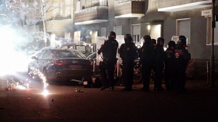 Archivbild:Polizeibeamte stehen hinter explodierendem Feuerwerk am 31.12.22. (Quelle:TNN)