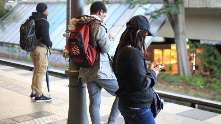 Symbolbild: Junge Erwachsene warten in Steglitz auf die S-Bahn und schauen auf ihr Smartphone. (Quelle: dpa/W. Steinberg)
