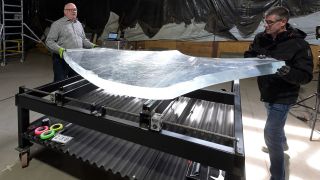 Materialprüfer Robert Kirchner (l) und Dienstleister Frank Kettler bewegen ein Bruchstück eines Aquariums, das auf einem speziellen Tisch liegt. (Quelle: dpa/M. Bahlo)