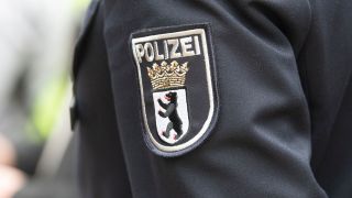 "Polizei" steht auf dem Wappen eines Polizeibeamten. (Quelle: dpa/Paul Zinken)