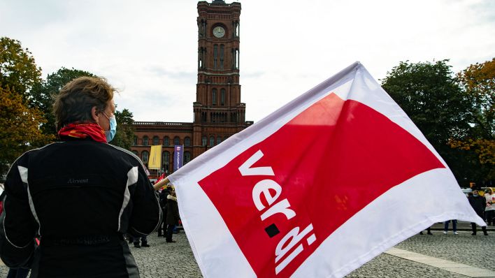 Eine Frau hält am Roten Rathaus eine Fahne mit dem Logo der Gewerkschaft Verdi in den Händen. (Quelle: dpa/Paul Zinken)