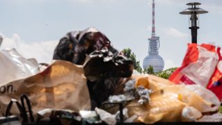 Der Berliner Fernsehturm ragt hinter einem vollen Mülleimer im Volkspark Friedrichshain hervor. (Quelle: dpa/Christoph Soeder)