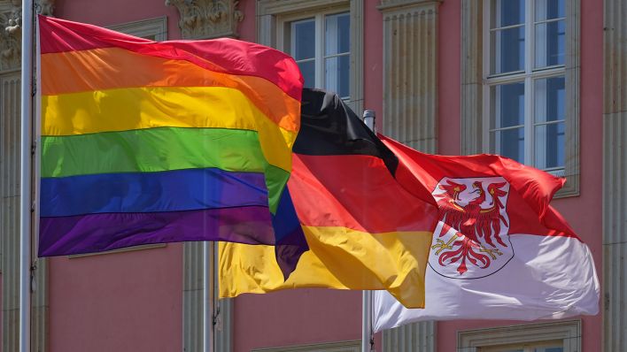 Die Regenbogenflagge (l) weht im Innenhof des Brandenburger Landtages neben den Flaggen der Bundesrepublik und des Landes Brandenburg (r). (Quelle: dpa/Soeren Stache)