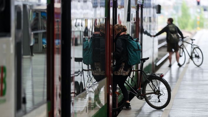 Zwei Reisende steigen mit ihren Fahrrädern in einen Zug. (Quelle: dpa/Jan Woitas)