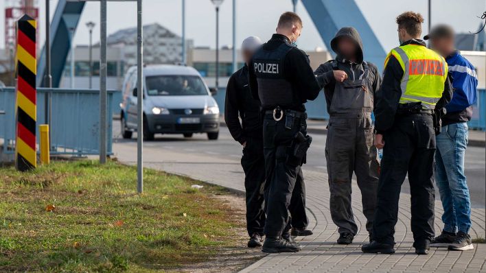 Archivbild: Zwei Polizisten kontrollieren auf der Grenzbrücke zwischen Deutschland und Polen drei Männer, die die Grenze zu Fuß überquerten. (Quelle: dpa/M. Skolimowska)