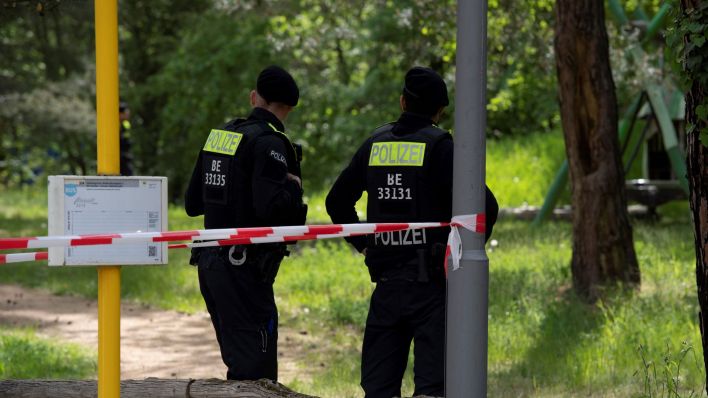 Polizeibeamte stehen an einer Grünanlage in Berlin-Gatow. In unmittelbarer Nähe wurde in den Mittagsstunden ein Mann von einem bislang Unbekannten erschossen. Der Tatverdächtige befindet sich auf der Flucht. (Quelle: dpa/Paul Zinken)