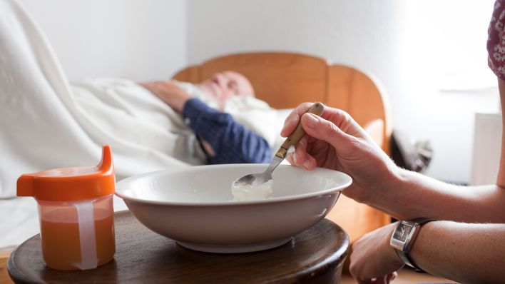 Symbolbild: Haeusliche Pflege - Eine Pflegerin reicht einem pflegebedürftigen Mann das Essen. (Quelle: dpa/U. Grabowsky)