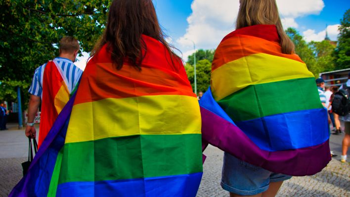 Zwei Frauen tragen eine Regenbogenfahne am Christopher Street Day. (Quelle: dpa/Marcel Ibold)