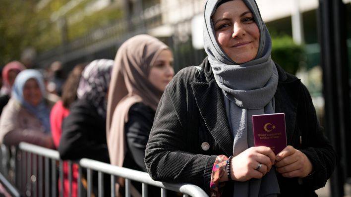Archivbild: Eine türkische Staatsbürgerin hält ihren Pass in der Hand, während sie vor dem türkischen Konsulat Schlange steht, um zu wählen. (Quelle: dpa/C. Ena)