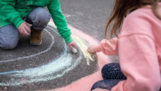 Symbolbild: Kinder malen auf einer Straße mit Malkreide. (Quelle: imago images)