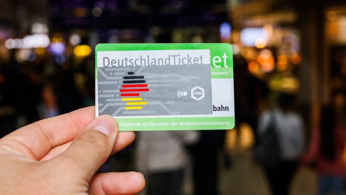 Deutschlandticket zwischen zwei Fingern eines Passagiers (Bild: imago images/Piero Nigro)