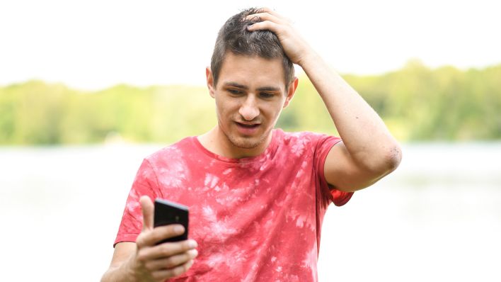 Symbolbild: Ein junger Mann schaut erschrocken auf sein Smartphone (Quelle: dpa/Tobias Hase)