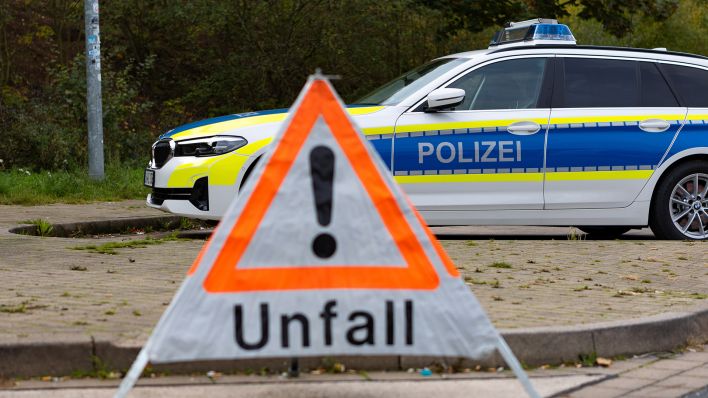 Symbolbild: An einer Straße steht ein faltbares Warndreieck der Polizei mit der Aufschrift Unfall. (Quelle: dpa/Fotostand)