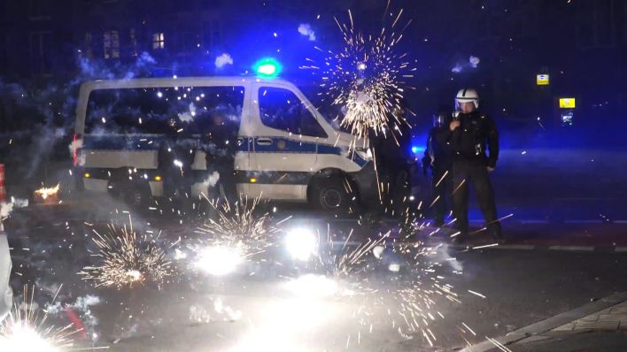 Polizeibeamte stehen am 01.01.2023 hinter explodierendem Feuerwerk. (Quelle: dpa/TNN/Julius-Christian Schreiner)