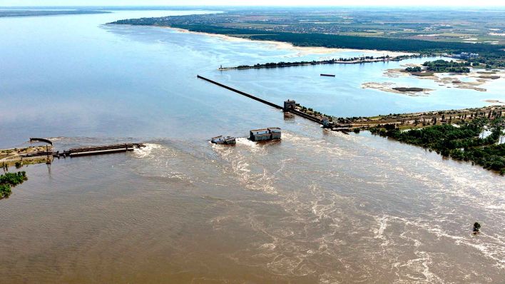 Wasser fließt über den zerstörten Staudamm. Wenige Tage nach der Zerstörung des Kachowka-Staudamms in der Südukraine ist Präsident Selenskyj in die Hochwasserregion gereist.(Foto: picture alliance/dpa/AP )