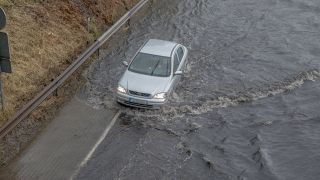 Ein Auto fährt am 26.06.2023 durch die überschwemmte A100 Autobahn (Quelle: dpa/Michael Kuenne)