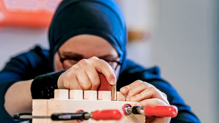 Symbolbild:Eine gefluchtete Frau mit Kopftuch arbeitet in einer Werkstatt.(Quelle:dpa/M.Gottschalk)