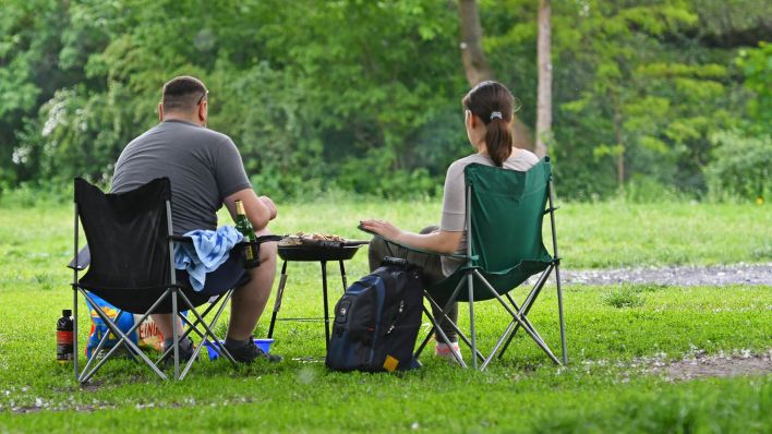 Symbolbild:Eine Frau und ein Mann sitzen im Volkspark Friedrichshain vor einem Grill.(Quelle:dpa/P.Zinken)