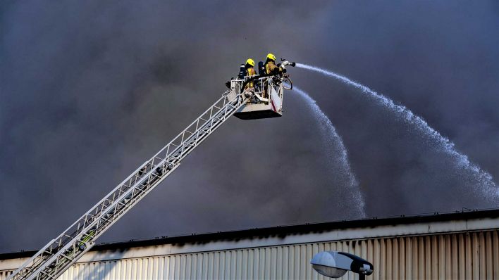 Feuerwehrleute kämpfen gegen das Großfeuer und die dichten Rauchschwarden. (Foto: dpa)
