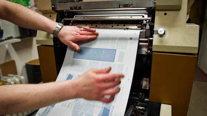 Archivbild:Ein Mann spannt in der Druckerei der Lichtblick-Redaktion im Gefängnis Tegel in Berlin, eine Druckplatte in die Druckmaschine ein.(Quelle:dpa/O.Spata)