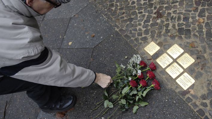 Ein Passant legt in Berlin vor "Stolpersteinen" zur Erinnerung an die Opfer des Nationalsozialismus Blumen nieder. (Quelle: dpa/Klaus-Dietmar Gabbert)