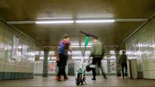 Passanten gehen in der U-Bahnstation Schönleinstraße an einem E-Scooter vorbei, der auf einem Treppenabsatz abgestellt wurde. (Quelle: dpa/Stefan Jaitner)
