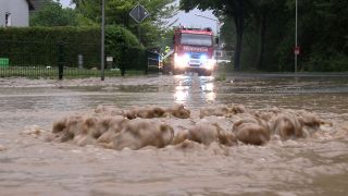 Symbolbild: Hochwasser. Wasser tritt aus einem Gullydeckel. (Quelle: dpa/Bernd März)