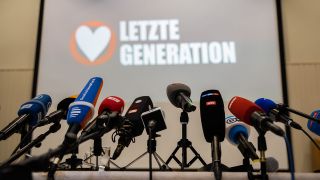 Mikrofone stehen vor Beginn einer Pressekonferenz der Letzten Generation (Quelle: dpa/Christoph Soeder)