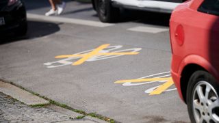 Auf der Ollenhauer Straße sind die Zeichen für den Radweg mit gelben Kreuzen zugeklebt und Autos parken darauf. (Quelle: dpa/Annette Riedl)