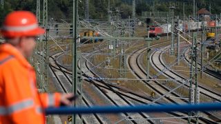 Symbolbild: Ein Bauarbeiter beobachtet den Güterverkehr auf Gleisen der Deutschen Bahn. (Quelle: dpa/S. Willnow)