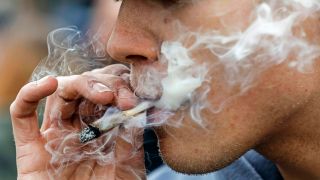 Symbolbild:Ein junger Mann raucht einen Joint.(Quelle:imago images/J.Eckel)