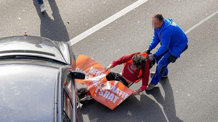 Ein Verkehrsteilnehmer versucht in Berlin, einen Aktivisten der "Letzten Generation" von der Straße zu schleppen (dpa/Marc Vorwerk/SULUPRESS.DE)