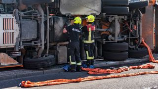 Einsatzkräfte der Feuerwehr stehen am 31.05.2023 an einem umgekippten Müllwagen der BSR. (Quelle: dpa-Bildfunk/Paul Zinken)
