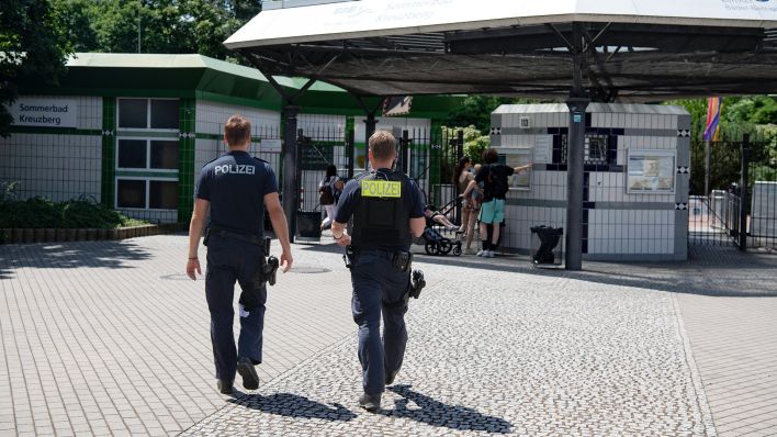 Zwei Polizsten der Mobilen Wache gehen auf das Prinzenbad in Kreuzberg zu (Quelle: dpa/Paul Zinken)