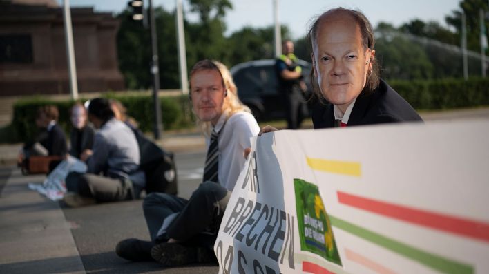 Mehrere Klimaaktivisten sitzen mit Masken von Politikern auf der Straße um den Großen Stern (Quelle: dpa/Paul Zinken).