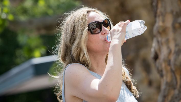 Symbolbild:Eine Frau trinkt aus einer Wasserflasche in einem Berliner Park.(Quelle:picture alliance/dpa/C.Klose)