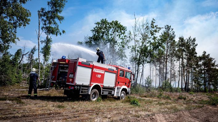 Symbolbild: Einsatzkräfte der Feuerwehr bekämpfen in einem Waldstück in Brandenburg das Feuer. (Quelle: dpa/F. Sommer)