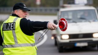 Symbolbild: Ein Polizeibeamter winkt mit einer Kelle einen Kleintransporter zu einer Verkehrskontrolle auf dem Autobahnparkplatz. (Quelle: dpa/P. Pleul)