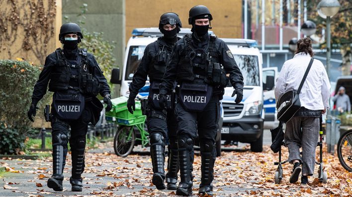 Symbolbild: Polizeibeamte gehen im Zuge einer Razzia auf einer Straße in Kreuzberg entlang. (Quelle: dpa/P. Zinken)