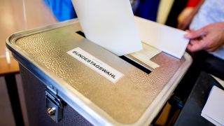 Beschreibung Ein Wähler wirft in einem Wahllokal, das im Klassenraum einer Grundschule im Stadtteil Prenzlauer Berg untergebracht ist, seinen Stimmzettel für die Bundestagswahl in eine Wahlurne. (Quelle: Hauke Christian Dittrich/dpa)