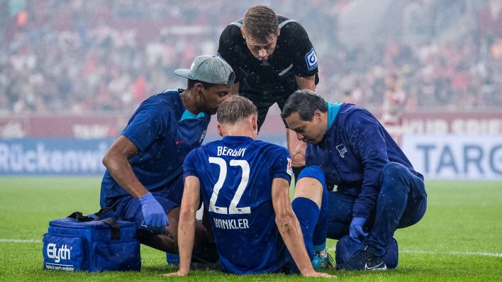 Hertha-Spieler Marten Winkler sitzt verletzt auf dem Rasen (Quelle: IMAGO / Beautiful Sports)