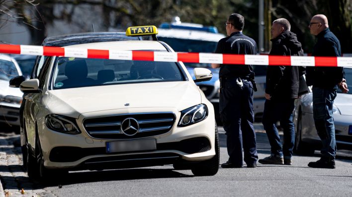 Mitarbeiter der Berliner Polizei stehen am 06.04.2023 nach einem tätlichen Vorfall vor einem Taxi in Berlin-Grunewald. (Quelle: dpa/Fabian Sommer)
