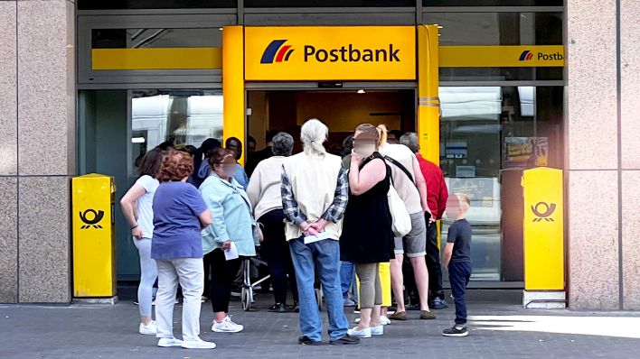 Symbolbild: Kunden stehen in einer Warteschlange vor einer Filiale einer Postbank. (Quelle: dpa/Kirchner-Media)