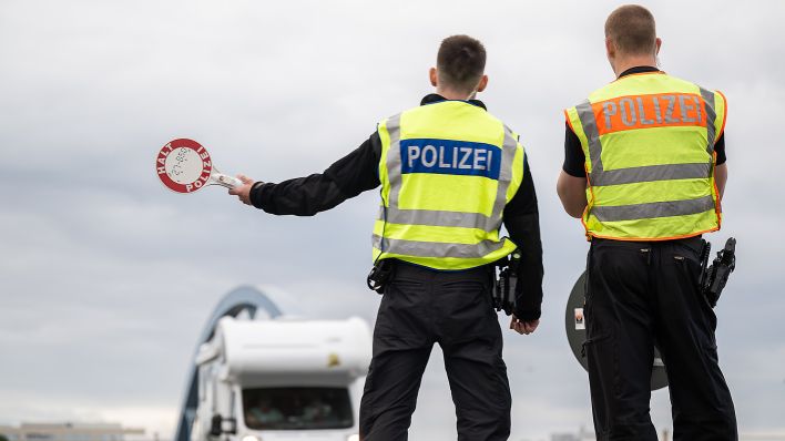 Ein Polizist winkt am 27.07.2023 einWohnmobil mit der Haltekelle heraus. An deutschen Grenzen wurden im ersten Halbjahr 2023 mehr unerlaubte Einreisen von der Bundespolizei registriert als im Jahr zuvor. (Quelle: Picture Alliance/Hannes P. Albert)