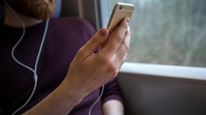 Symbolbild:Ein Mann benutzt sein Handy im Zug.(Quelle:dpa-tmn/C.Klose)