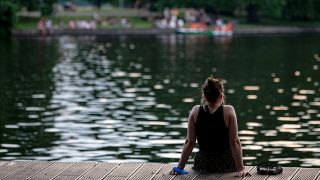 Symbolbild:Eine Frau sitzt am Ufer der Spree und genießt die sommerlichen Temperaturen.(Quelle:dpa/F.Sommer)