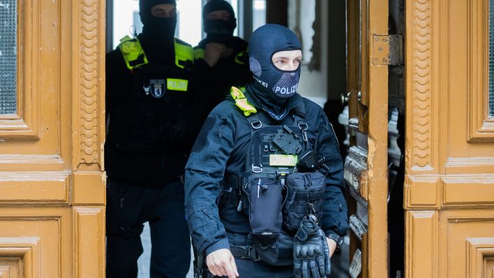 Archivbild: Polizisten kommen bei einer Hausdurchsuchung in Berlin-Kreuzberg aus einem Gebäude. (Quelle: dpa/C. Soeder)